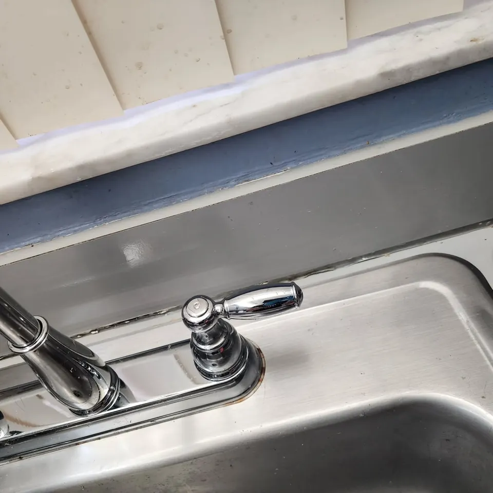 The same kitchen faucet after cleaning, polished chrome and a clean sink edge