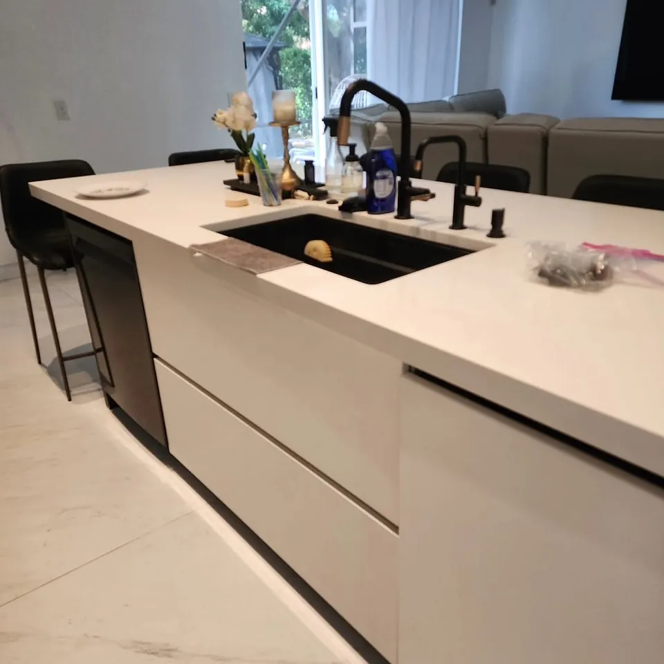 The same kitchen island after cleaning, clear white countertop and tidy sink