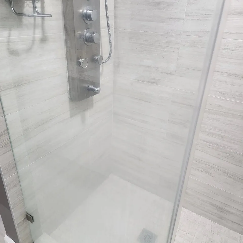 Clear glass shower door and light gray tile after a deep clean