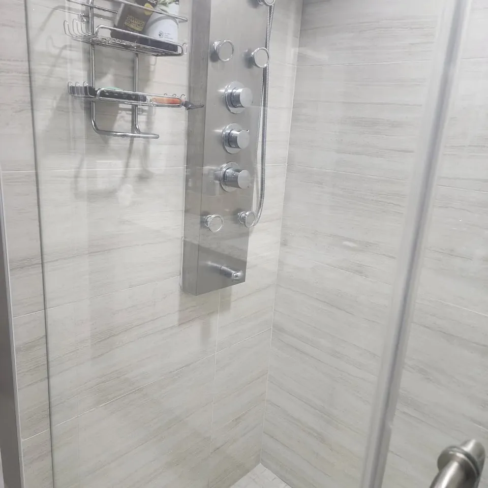 Glass walk-in shower with a stainless shower panel, freshly cleaned