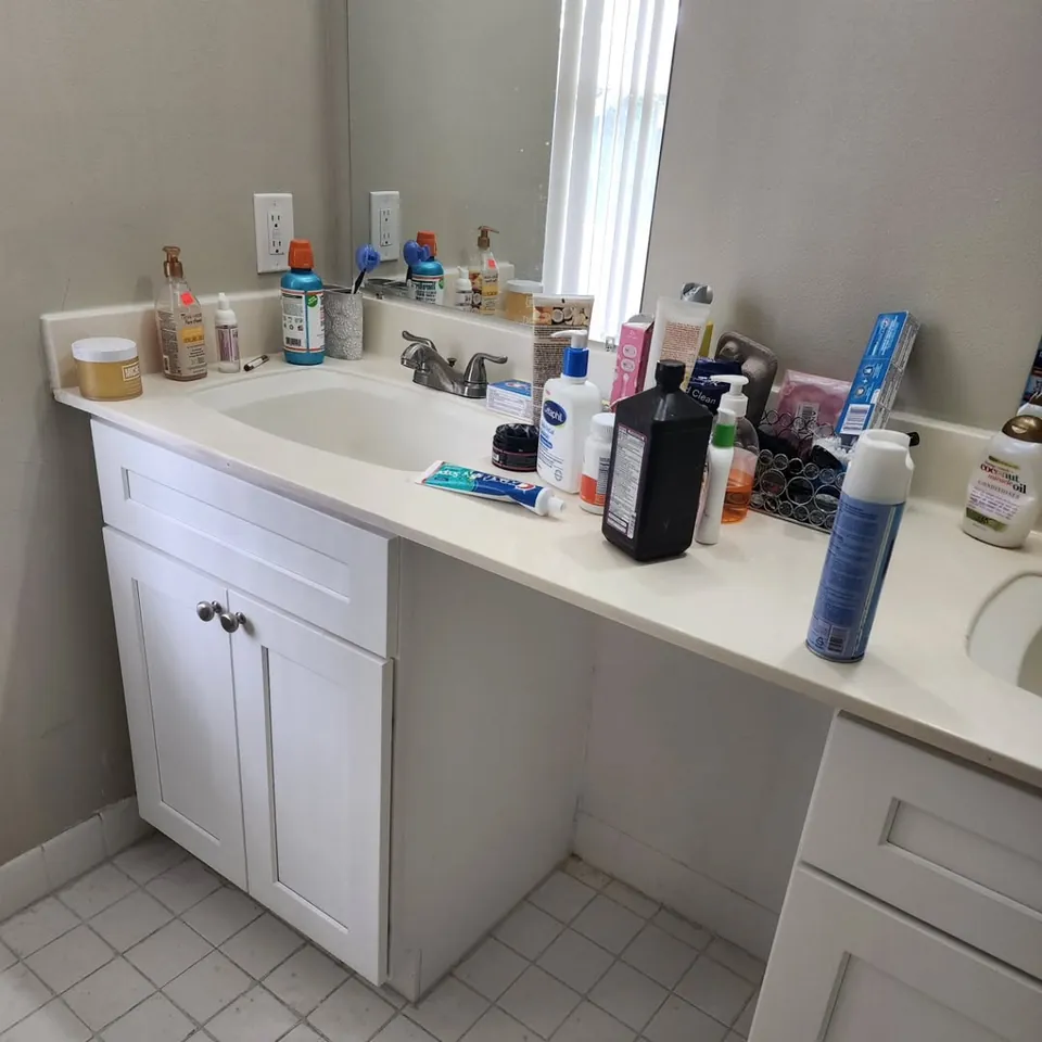 White bathroom vanity with the counter wiped down and products organized